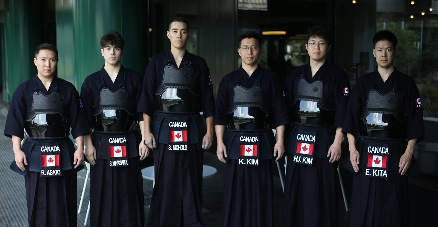 The six selected men of Team Canada standing shoulder to shoulder in do and hakama, each name plate reading CANADA