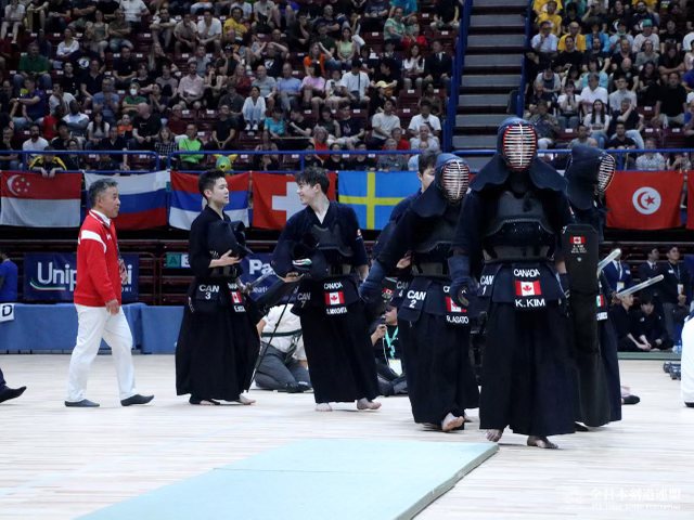 Team Canada walking onto the competition floor in bogu, the flags of competing nations hanging behind them